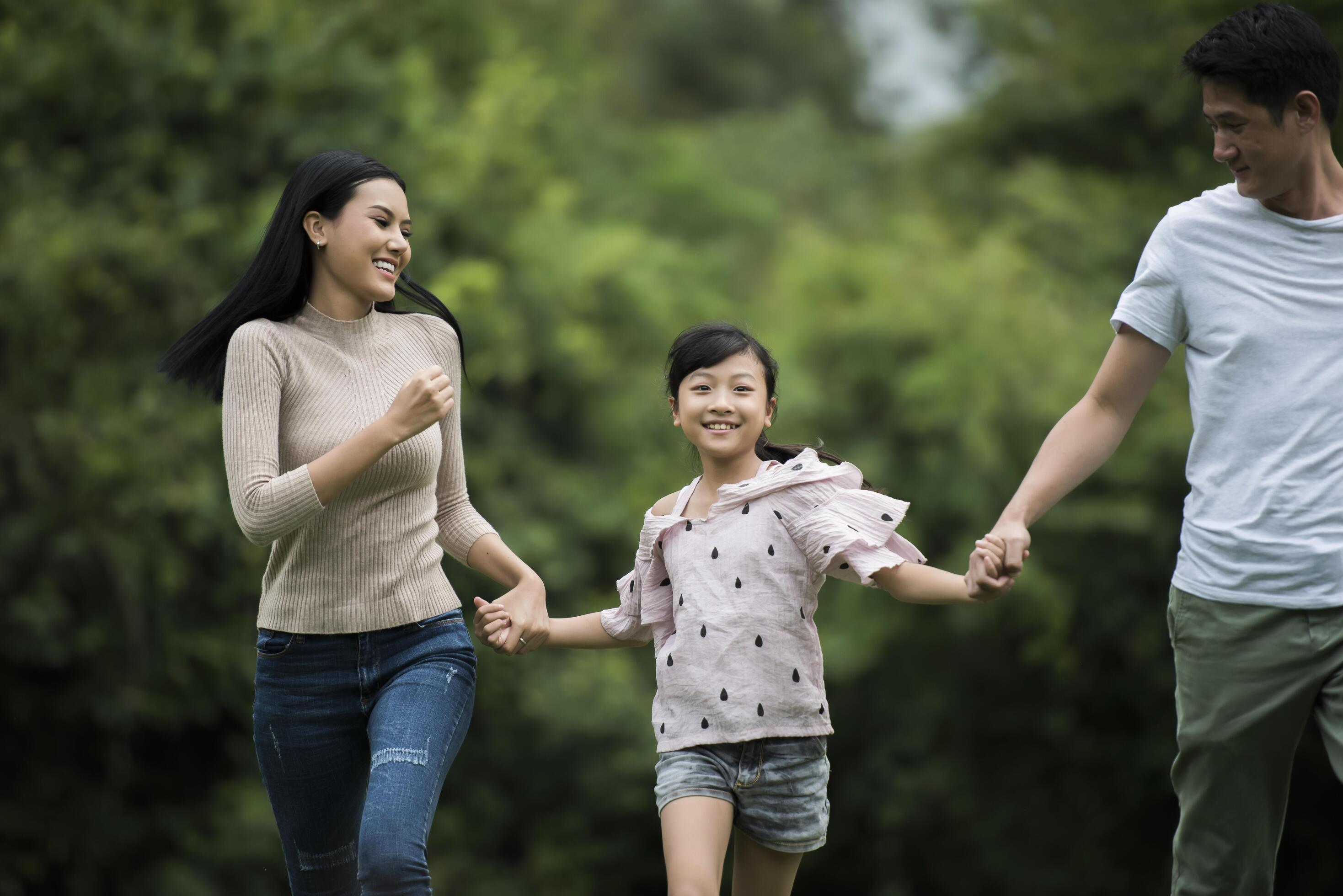 Happy family is having fun Mother, father and daughter are running in park. Stock Free