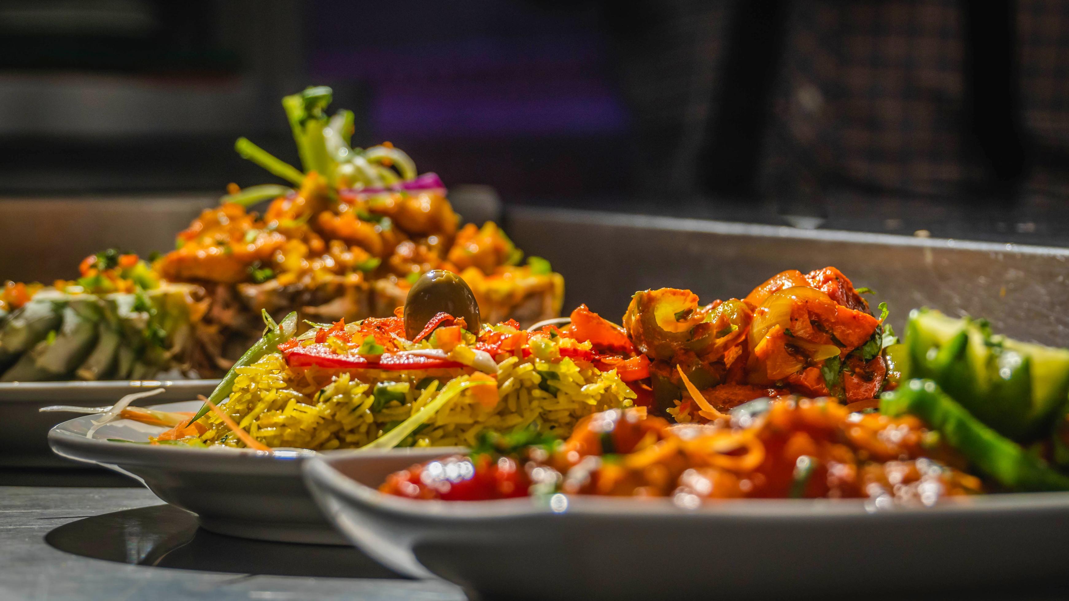 A table topped with lots of different types of food, colorful dramatic lighting, close up shot from the side. Stock Free