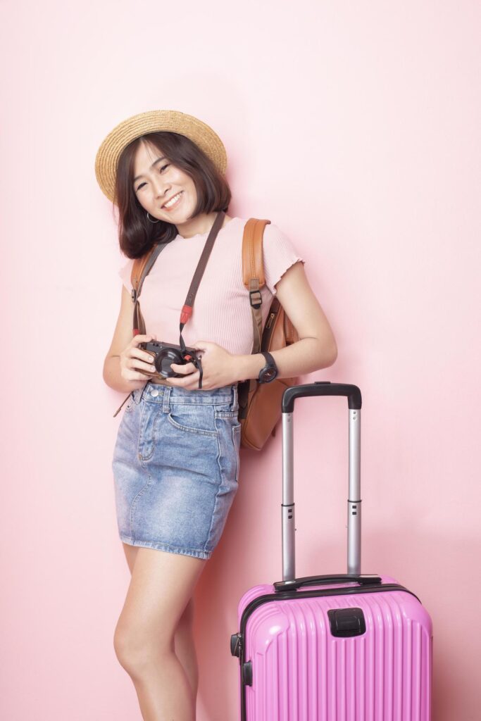 Happy Asian woman tourist on pink background Stock Free