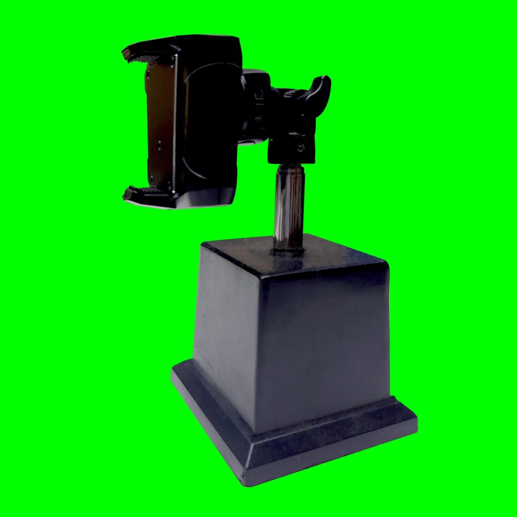 Smartphone holder, tool for photography, made of plastic and stainless with a green background texture Stock Free