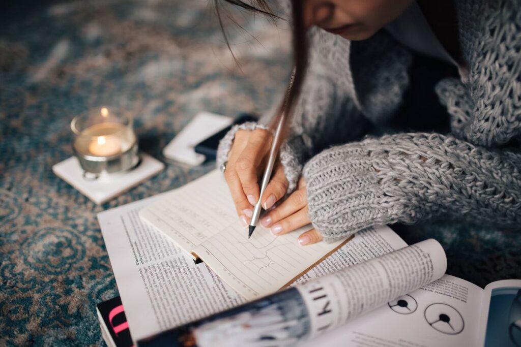 Woman in a grey sweater taking notes in an organizer Stock Free