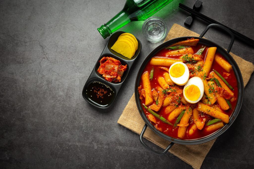 Cheesy Tokbokki korean traditional food on black board background. Lunch dish. Stock Free