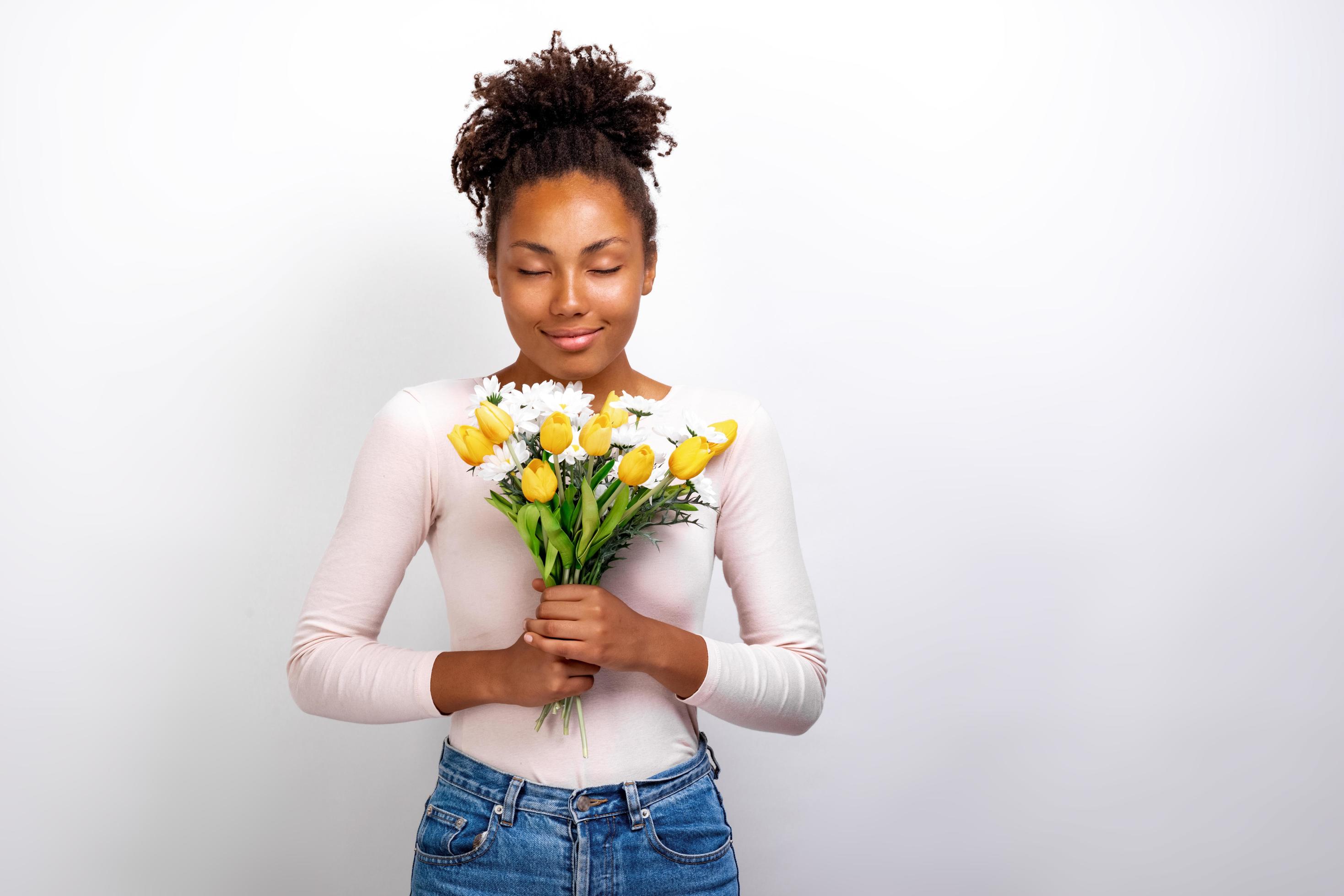 Half-length studio portrait of wonderful girl with bouquet of flowers tulips and daisies in her hands Stock Free