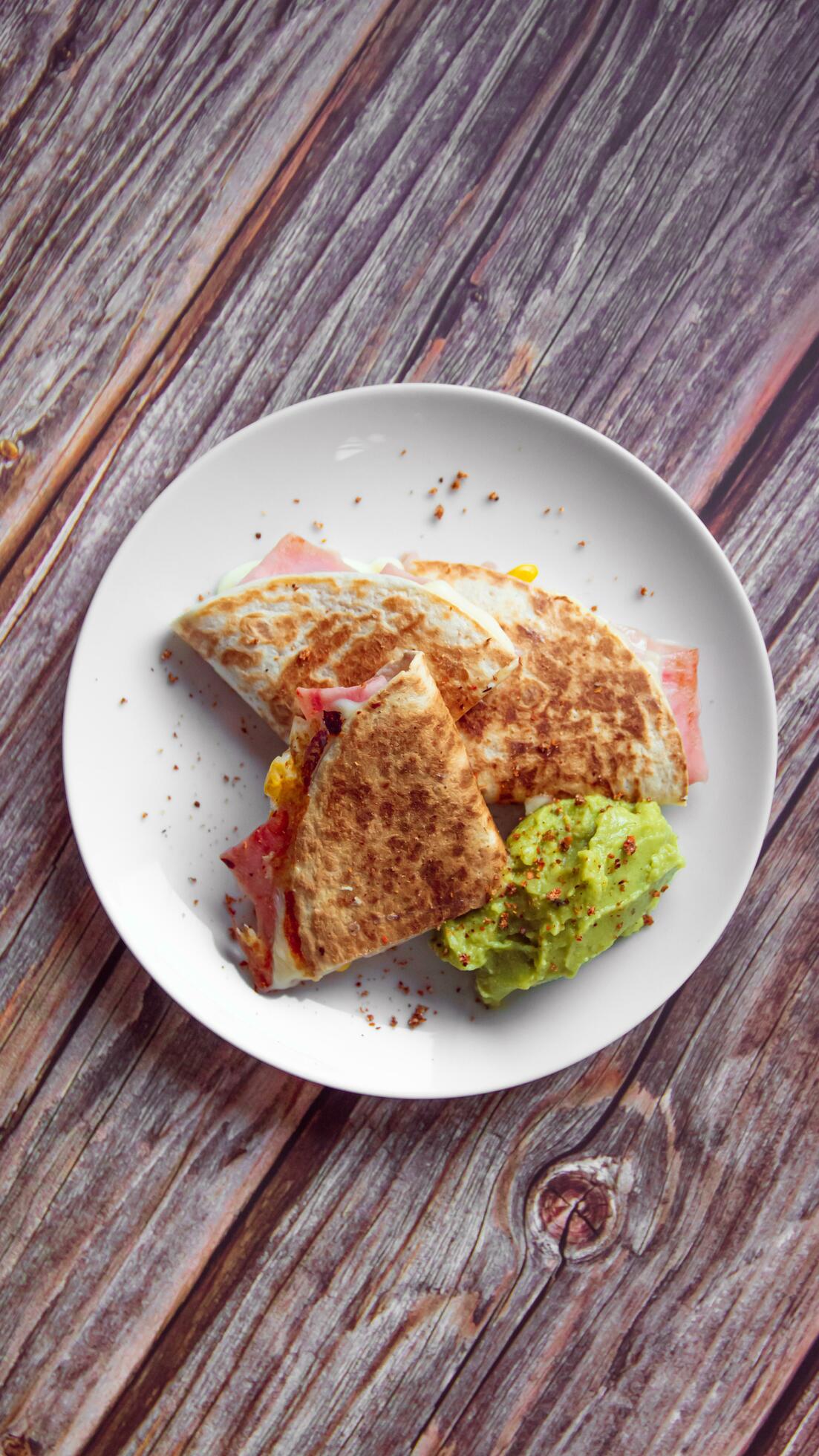 A plate of food with a quesadilla and guacamole on it. Stock Free