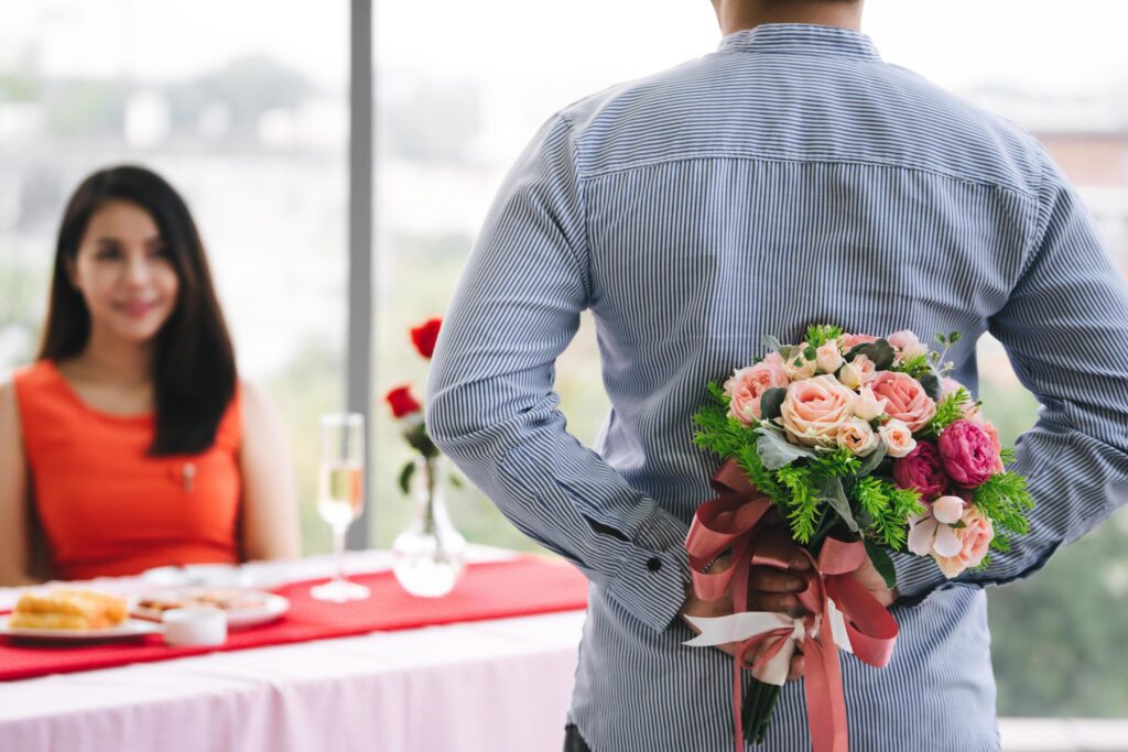 Lover with surpise flower bouquet at dinner table. Stock Free