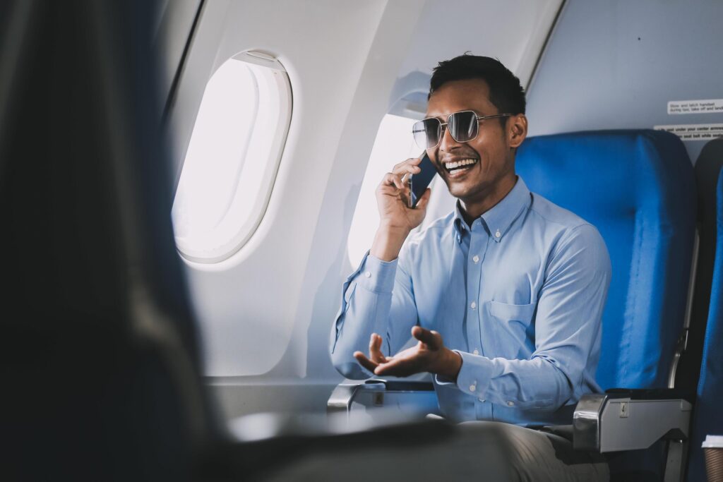 Traveling and technology. happy young businessman working on laptop computer and smartphone while sitting in airplane. Stock Free