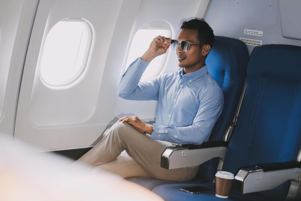 Traveling and technology. happy young businessman working on laptop computer and smartphone while sitting in airplane. Stock Free