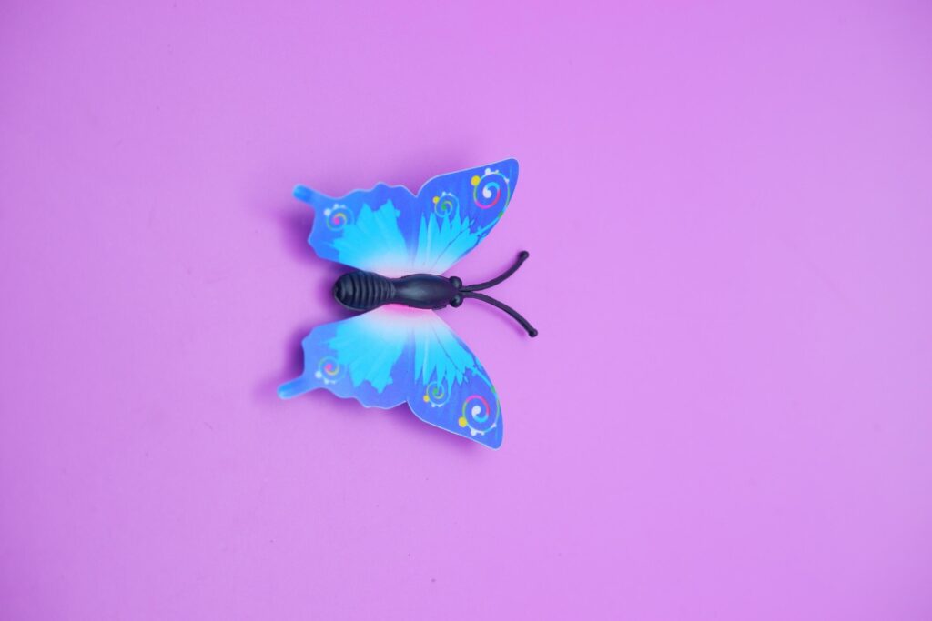 butterfly toy isolated on purple background. toy butterfly with blue wings. Stock Free