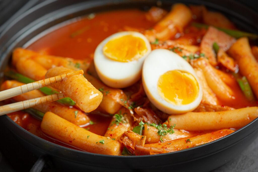 Cheesy Tokbokki korean traditional food on black board background. Lunch dish. Stock Free