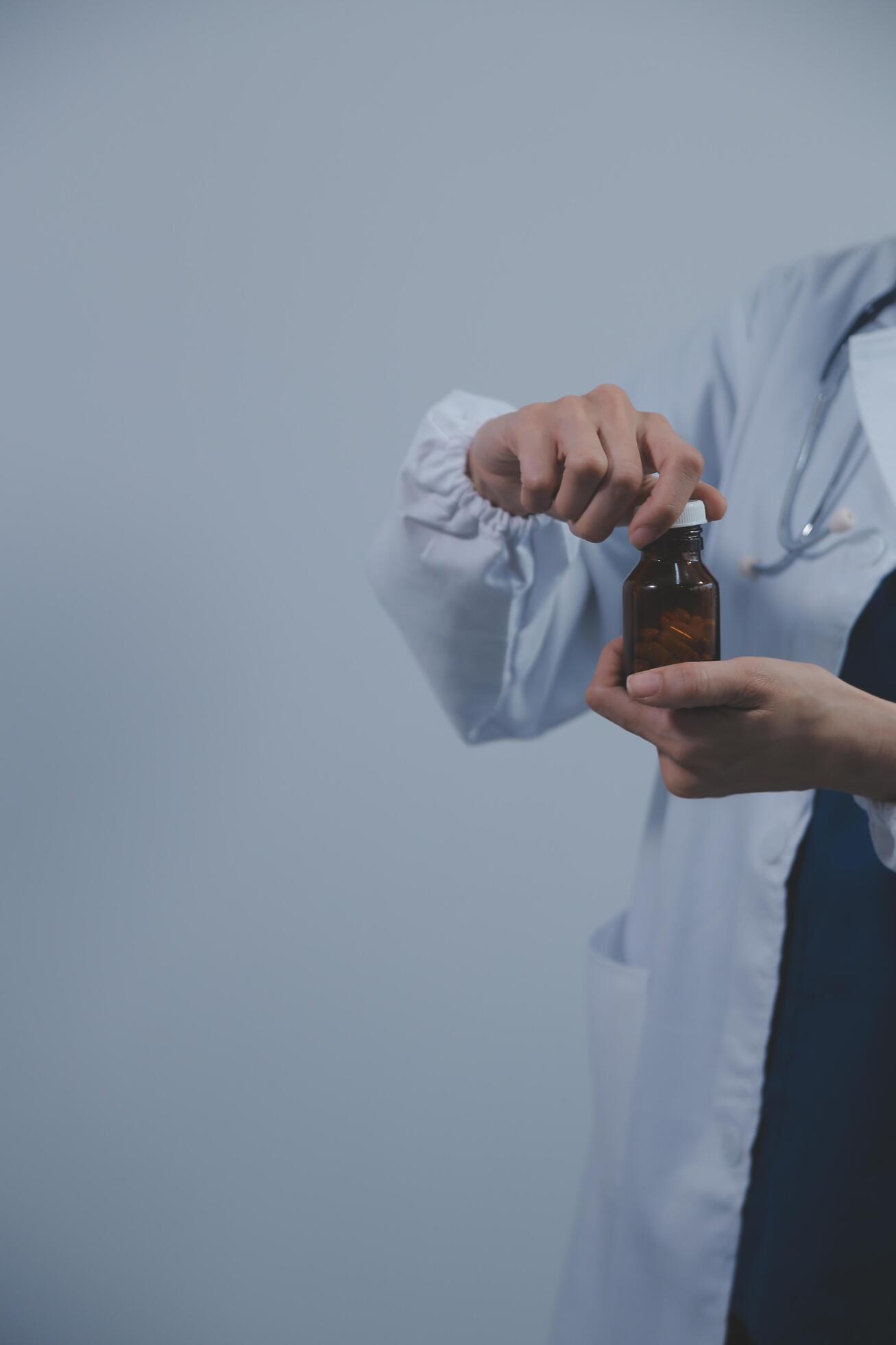 Southeast Asian medical doctor holding a bottle of pills, smiling isolated white background Stock Free