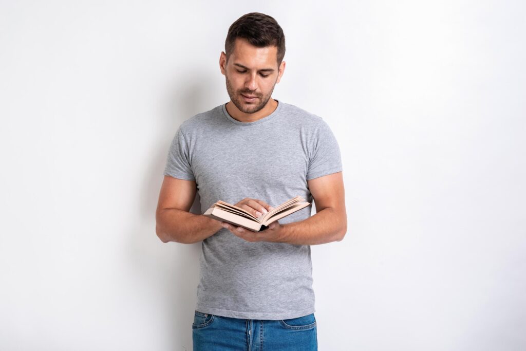 Studio shot of standing man holding a book and reading of it,- Education concept Stock Free