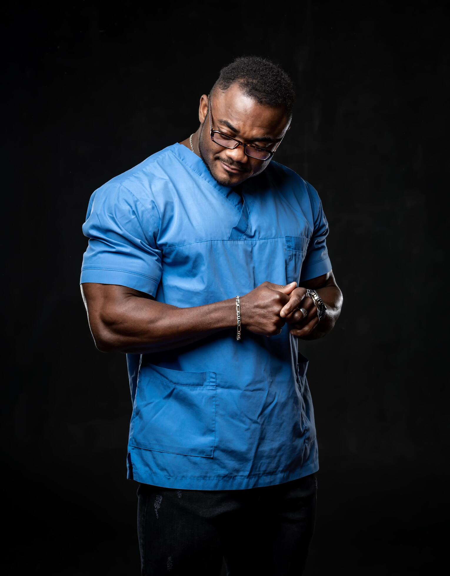 Handsome adult african american poses to the camera in light blue shirt on dark background. Male with strong hands. Closeup. Stock Free