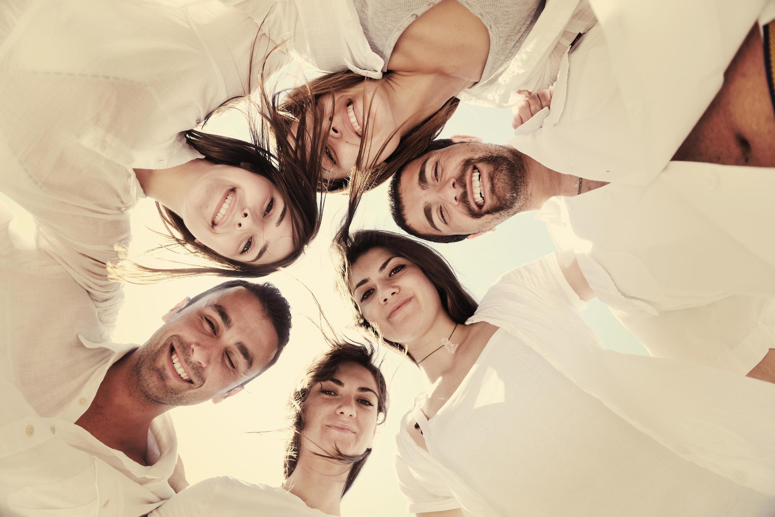 Group of happy young people in circle at beach Stock Free