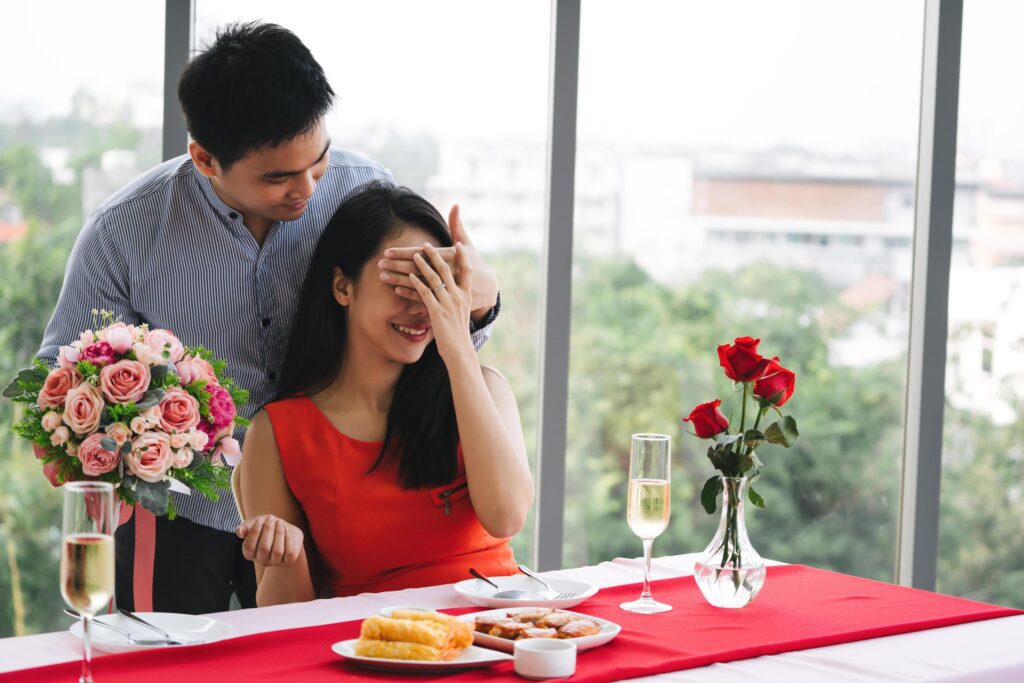 Lover with surpise flower bouquet at dinner table. Stock Free