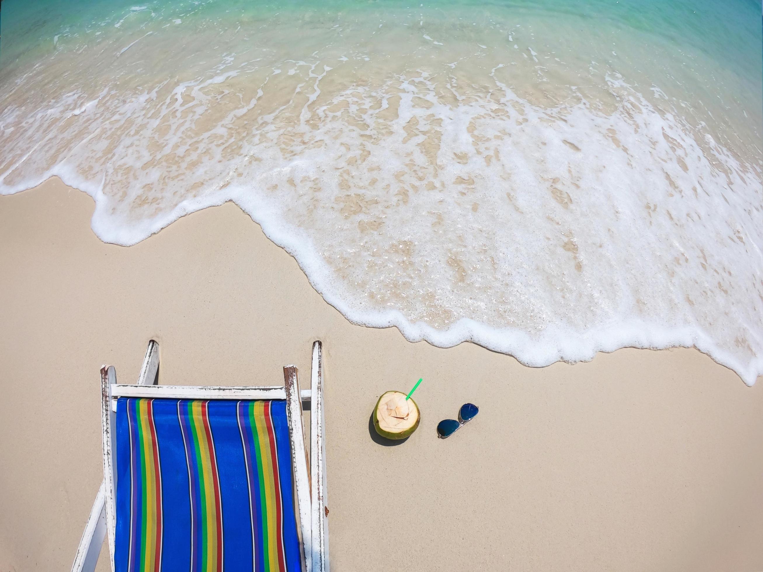 Relax beach chair with fresh coconut on clean sand beach with blue sea and clear sky – sea nature background relax concept Stock Free