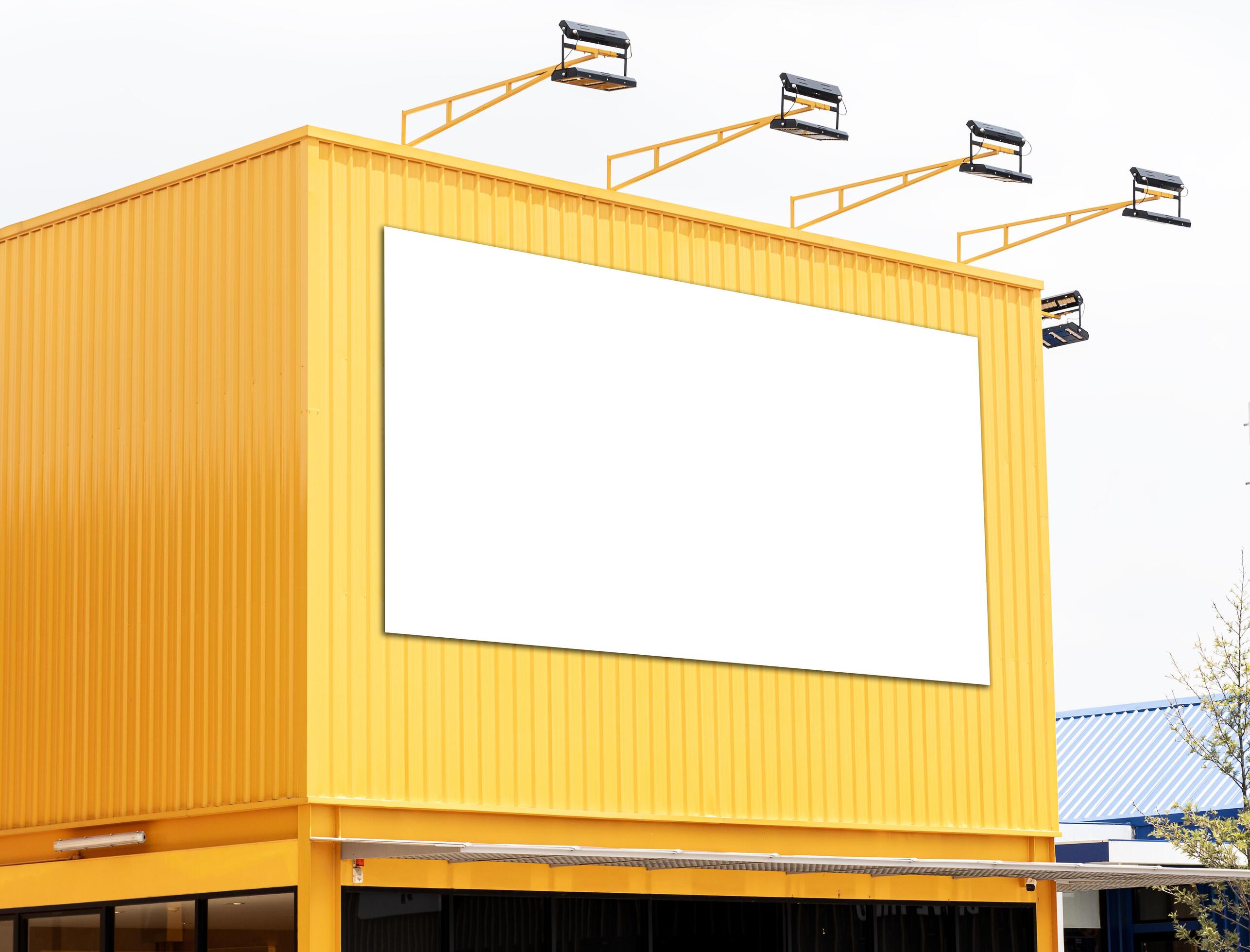 Mock up white background billboard on yellow building with spotlight. Clipping path for mockup Stock Free