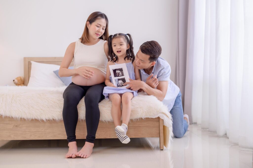 An Asian family, parents and daughters are watching an ultrasound film of a child in their mother’s womb Stock Free