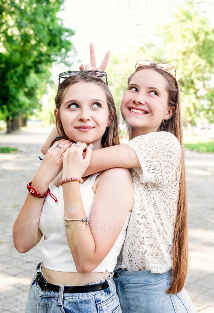 Happy girlfriends hugging together outdoors Pro Photo