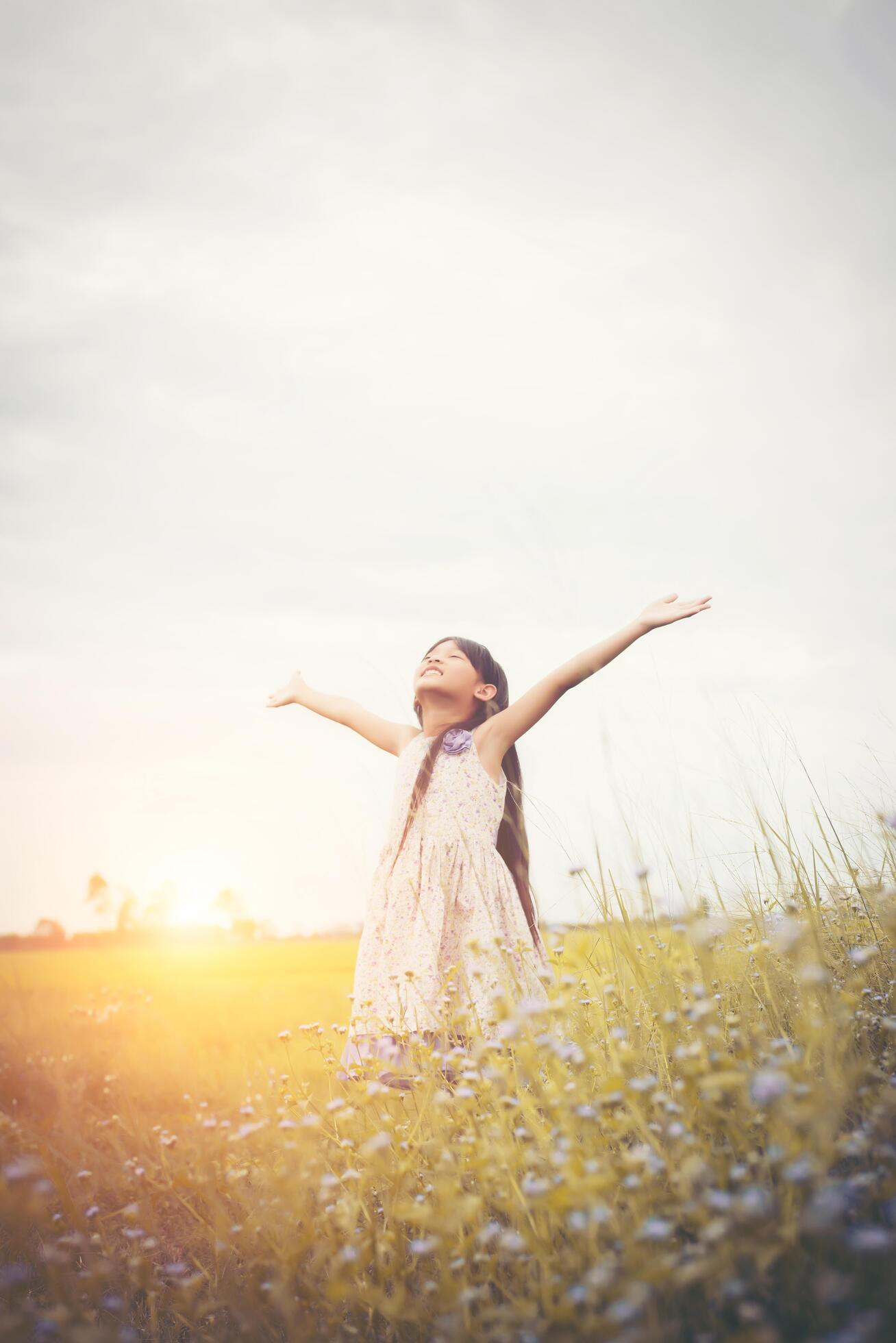 Little cute asian girl standing among the purple flower field sunshine day. Freedom enjoying with nature. Stock Free