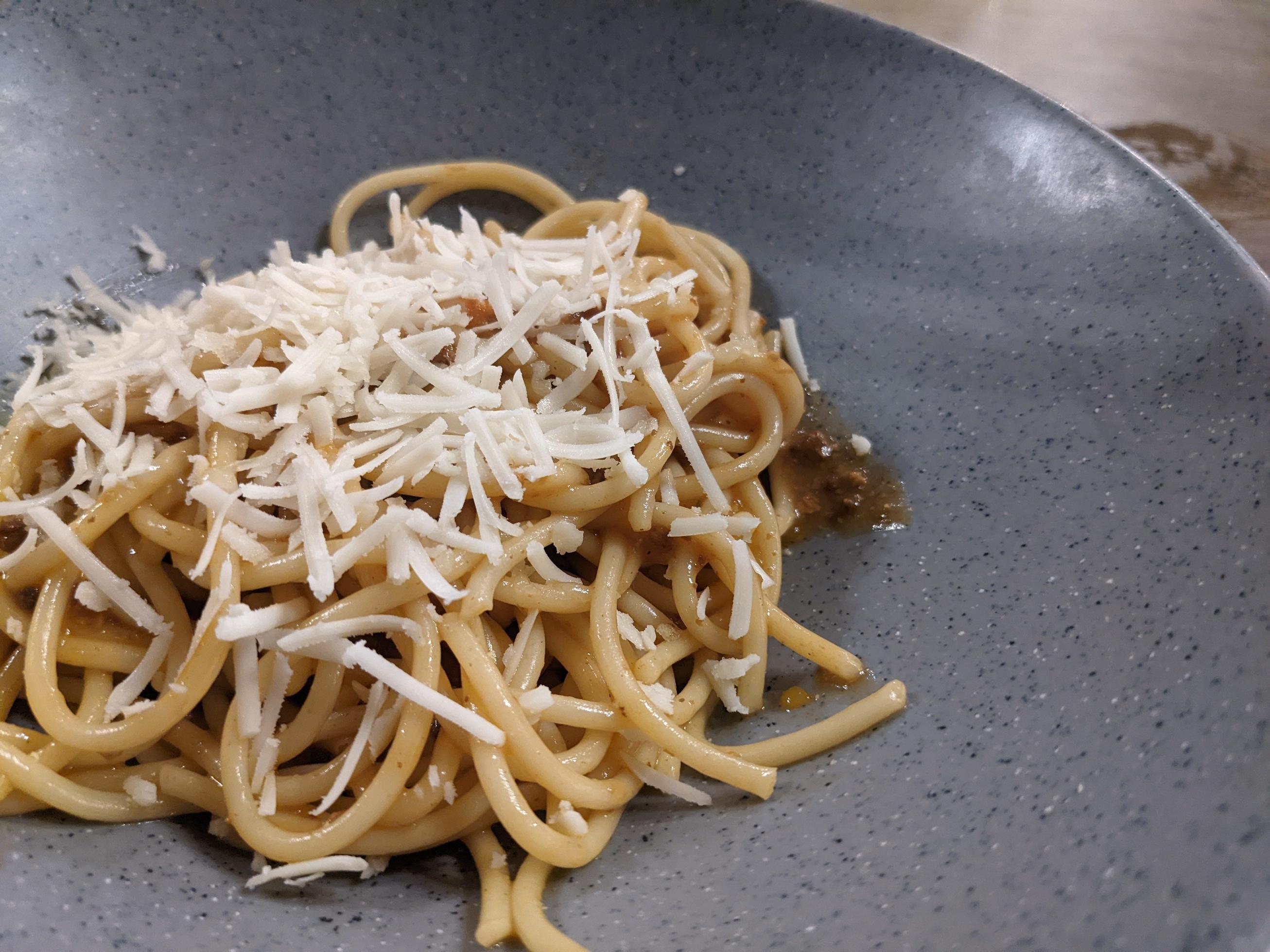 Spaghettis Bolognese with cheese cheddar topping on the grey bowl. The photo is suitable to use for food background, poster and food content. Stock Free