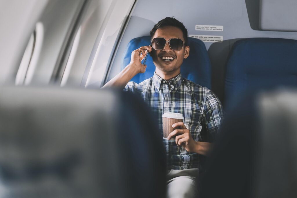 Traveling and technology. happy young businessman working on laptop computer and smartphone while sitting in airplane. Stock Free