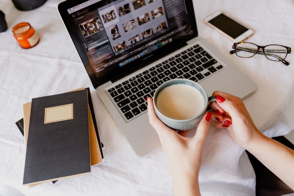 A woman works at a desk with a laptop and a cup of coffee Stock Free