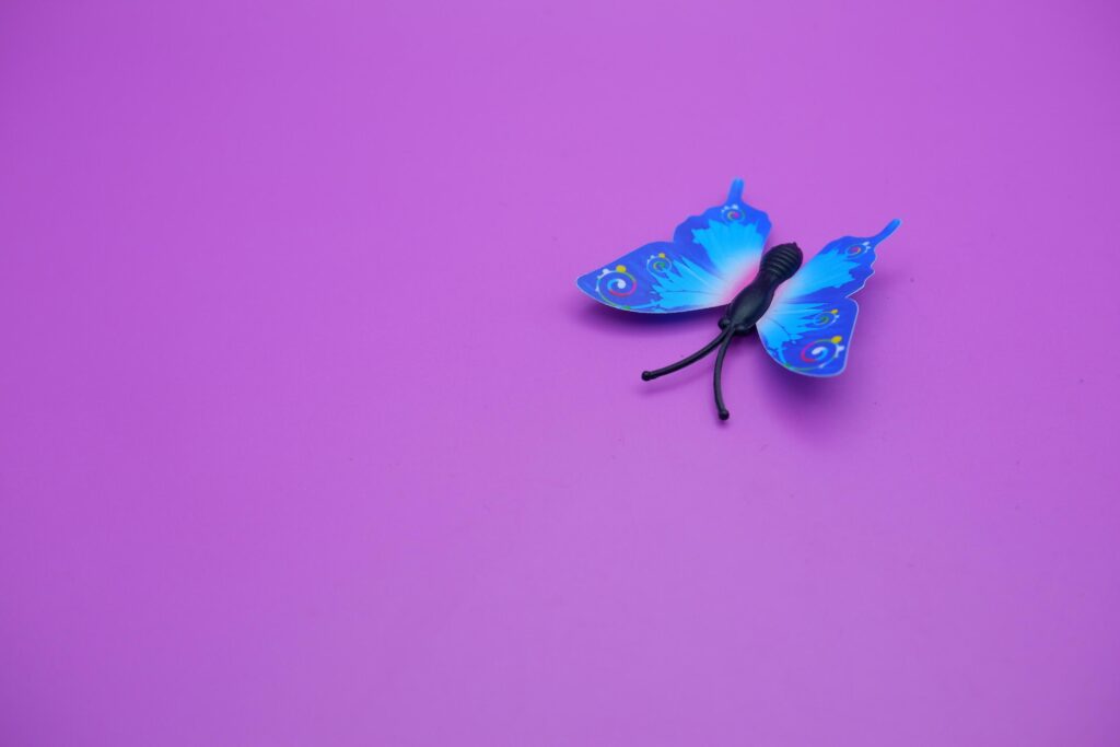 butterfly toy isolated on purple background. toy butterfly with blue wings. Stock Free