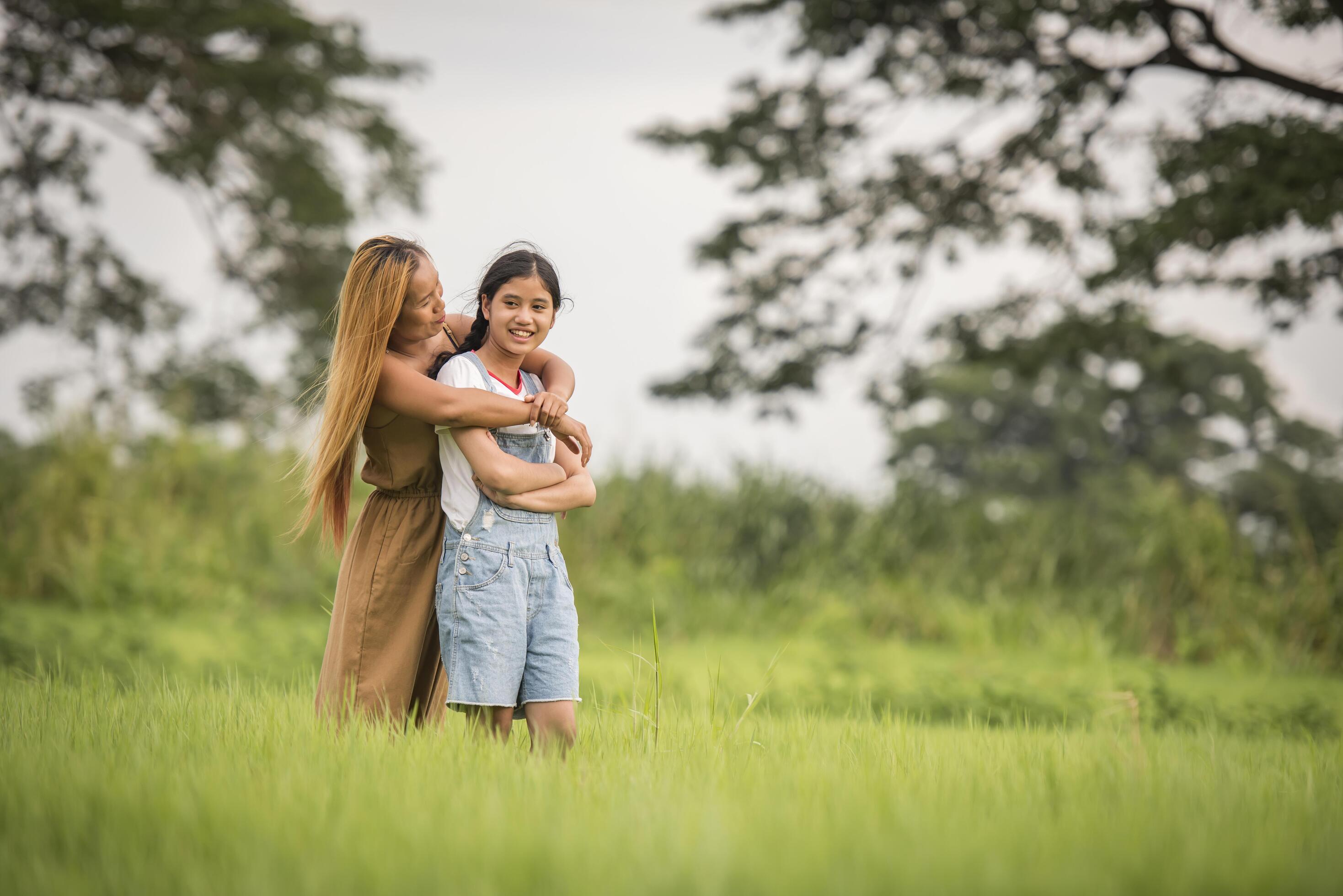 Mother and daughter standing happy in grass field Stock Free