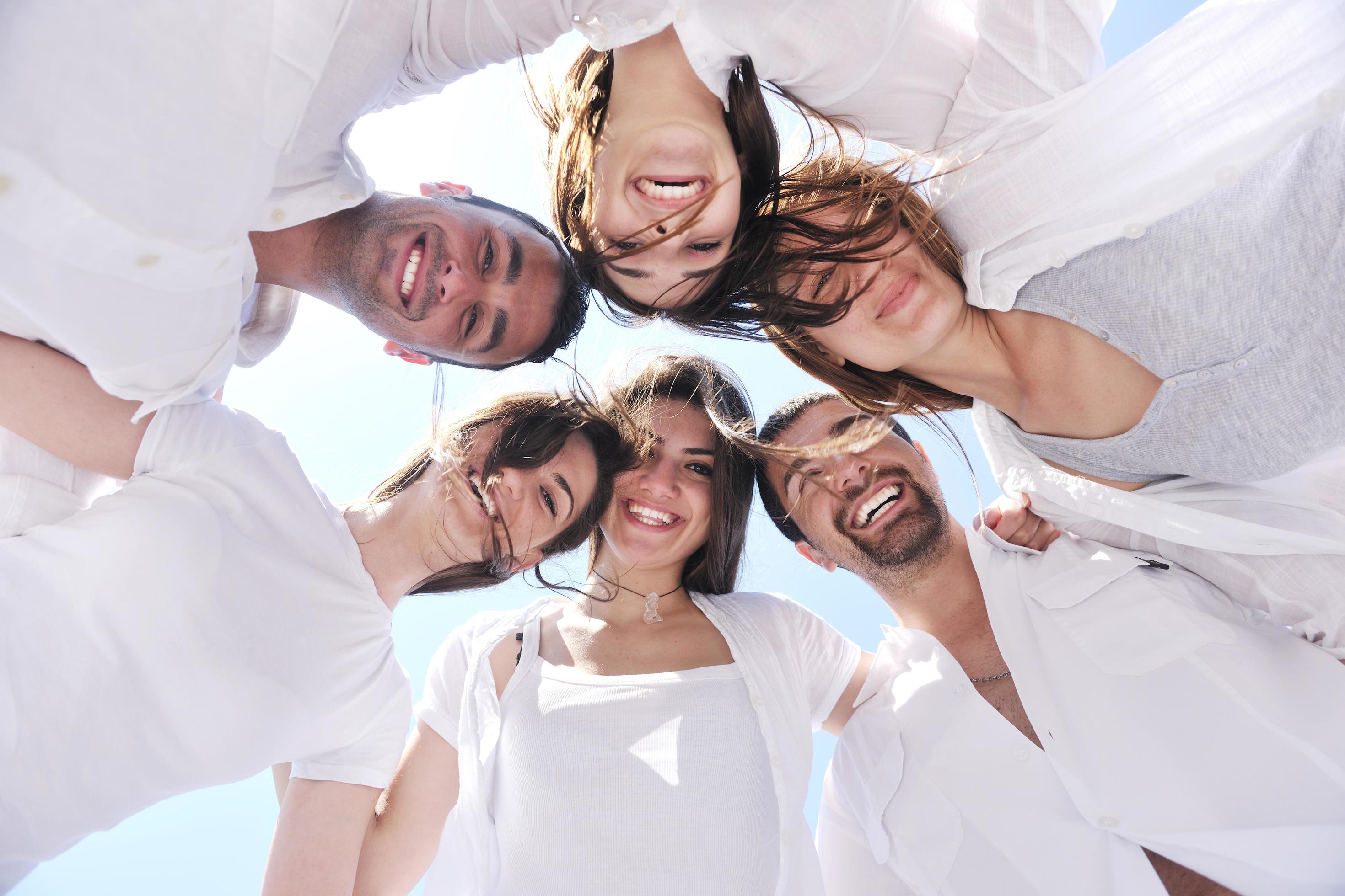 Group of happy young people in circle at beach Stock Free