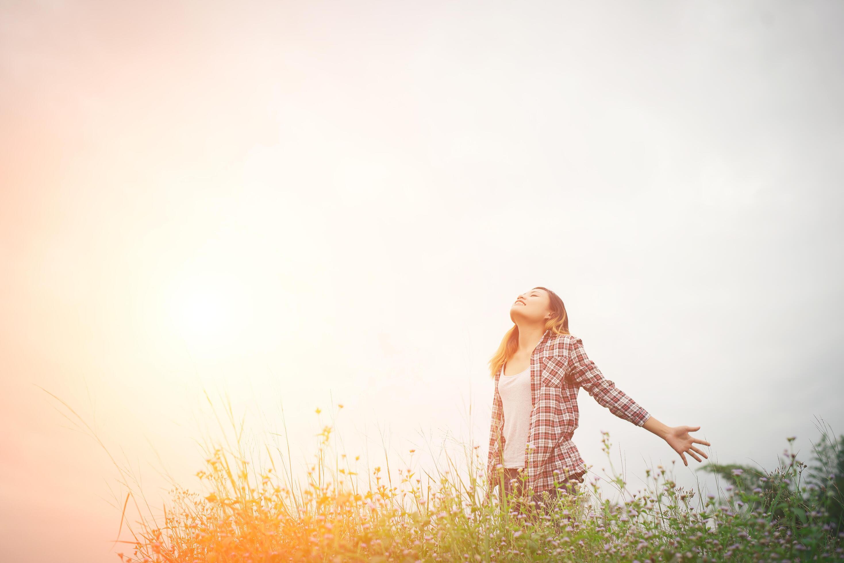 Young beautiful hipster woman in a flower field at sunset. Freedom enjoying with nature. Stock Free