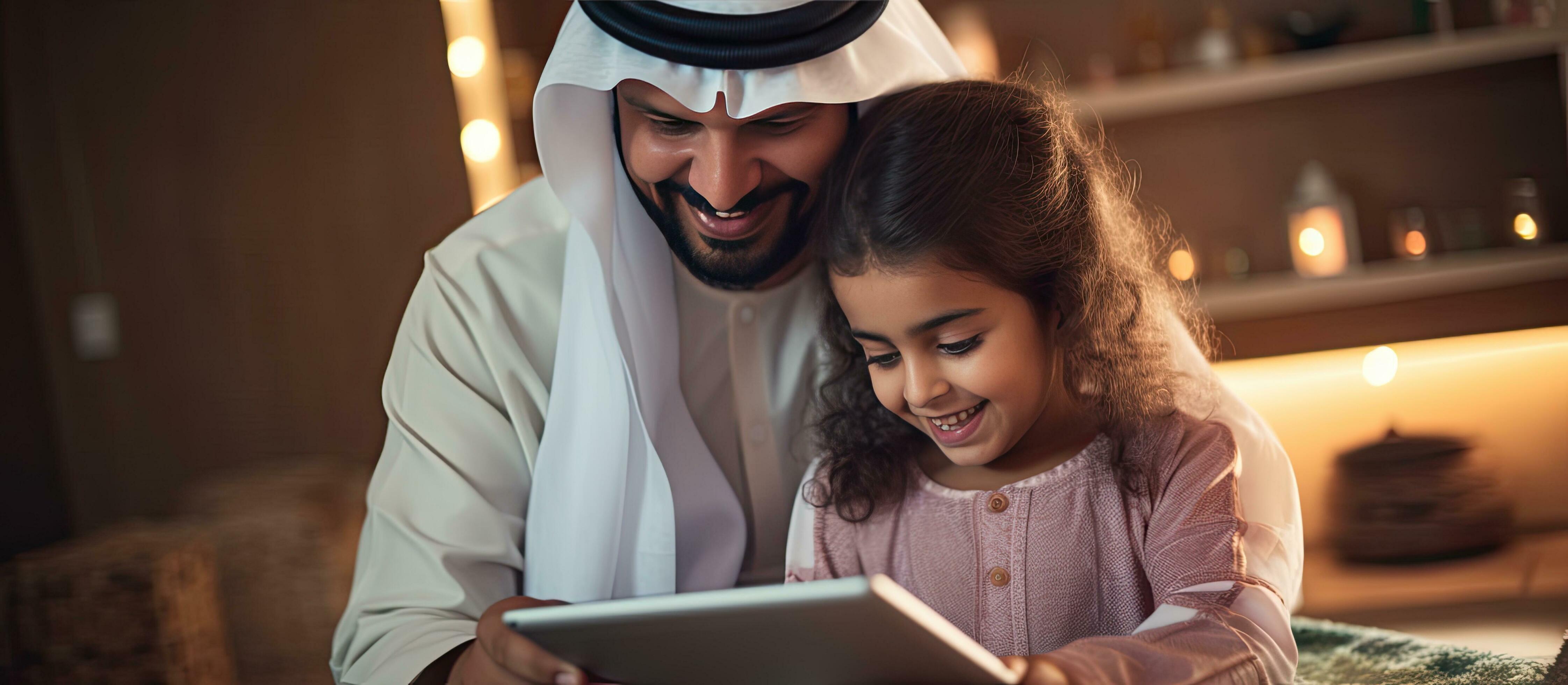 Young Arab father and his adorable daughter enjoying time together at home using a tablet for online shopping Stock Free