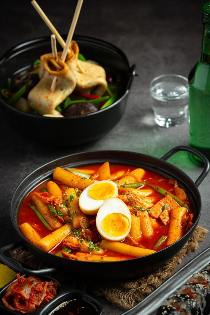 Cheesy Tokbokki korean traditional food on black board background. Lunch dish. Stock Free