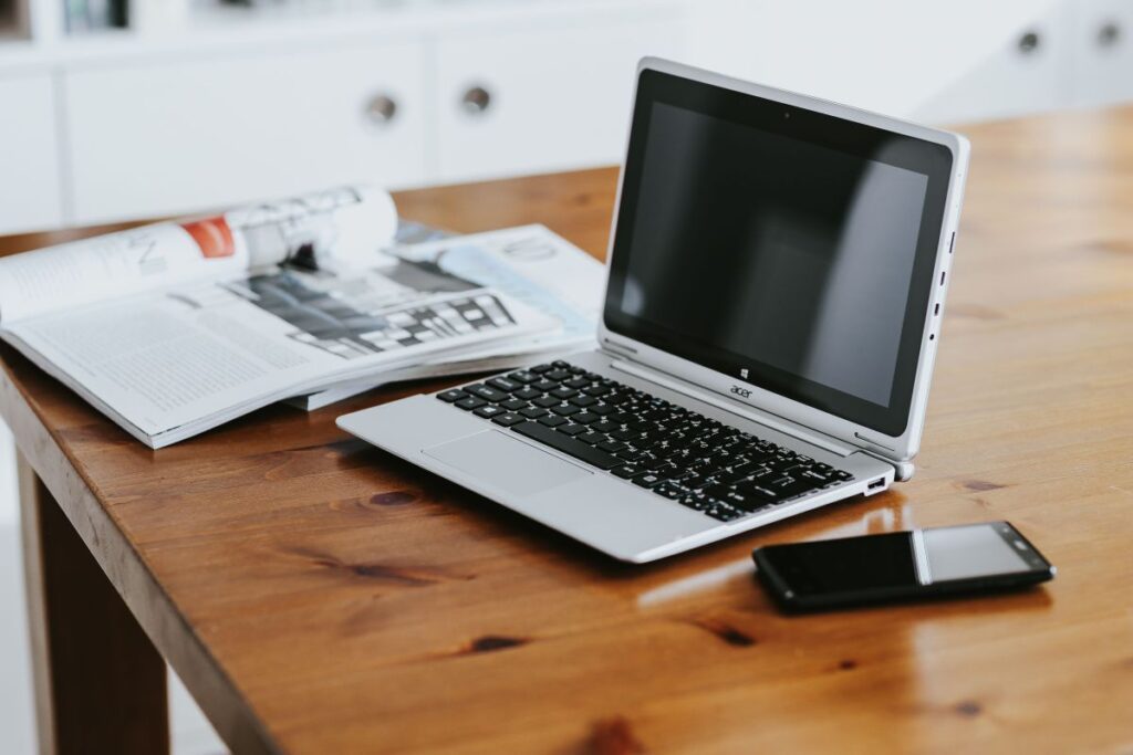 Silver laptop with various items on a table Stock Free