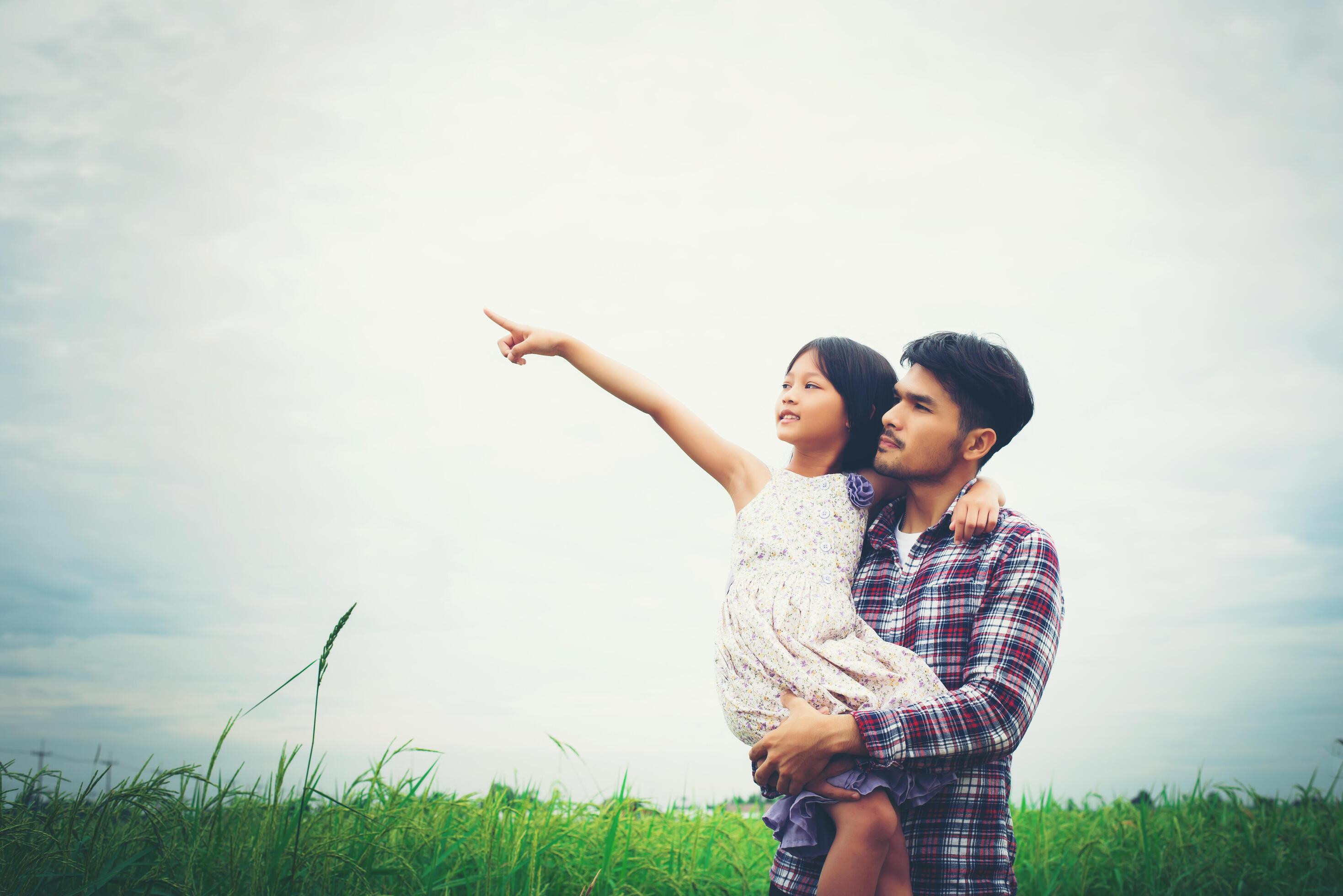 Daughter pointing away and smiling with her dad in the meadows field. Stock Free