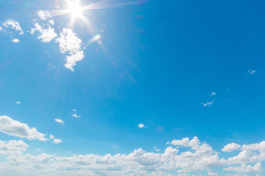 Natural abstract background of bright blue sky and fluffy white clouds on a sunny, light a flare and sun. Stock Free