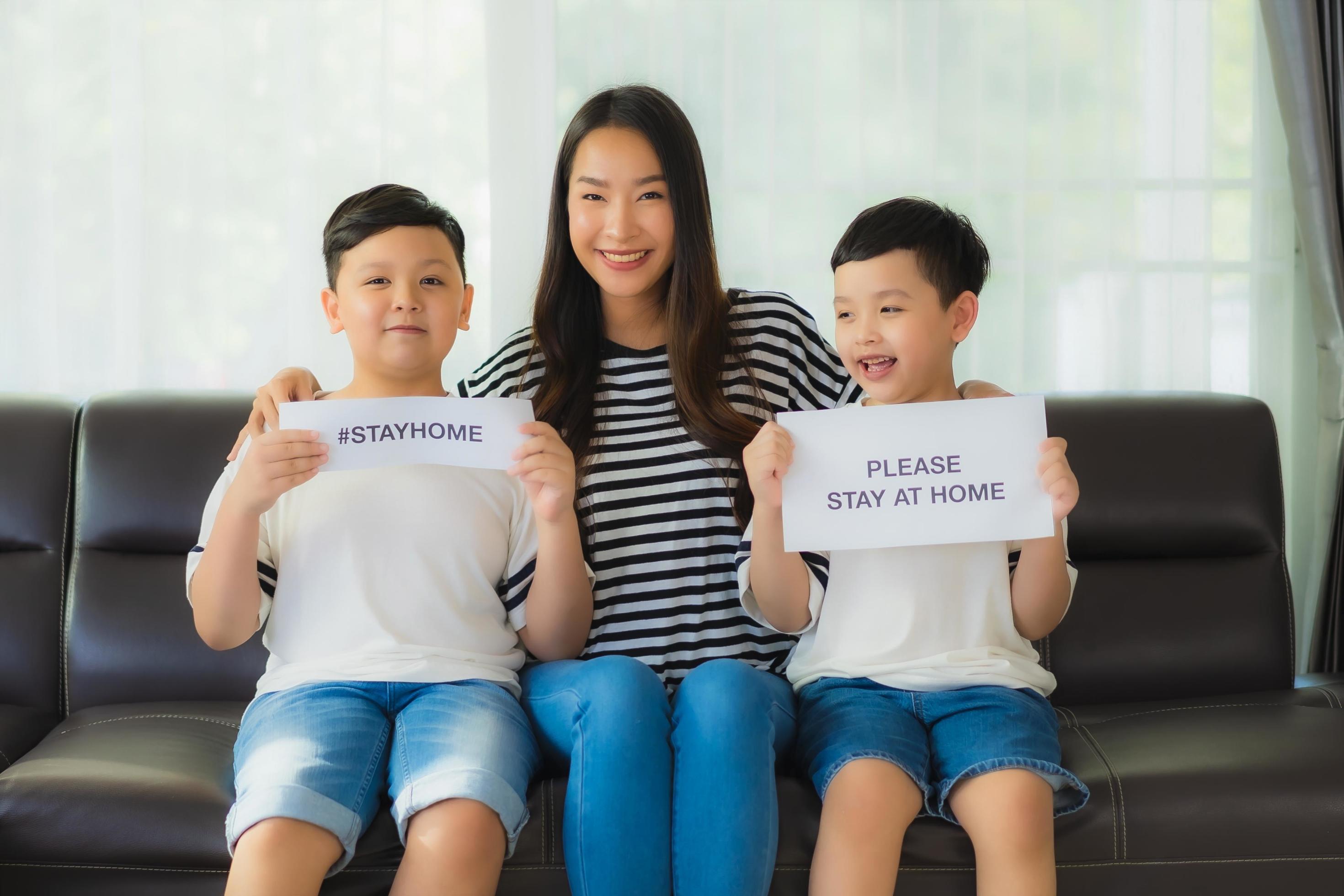 Mom with two sons holding up signs to stay home Stock Free