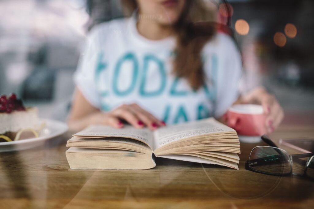 Woman reading book at coffee shop Stock Free