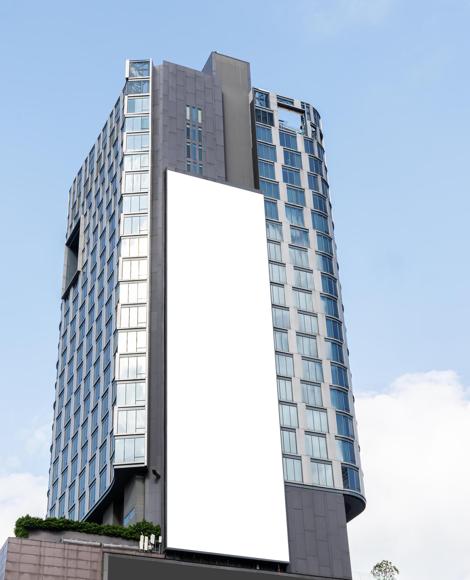 Mock up white vertical large LED display billboard on tower building with blue sky background .clipping path for mockup Stock Free