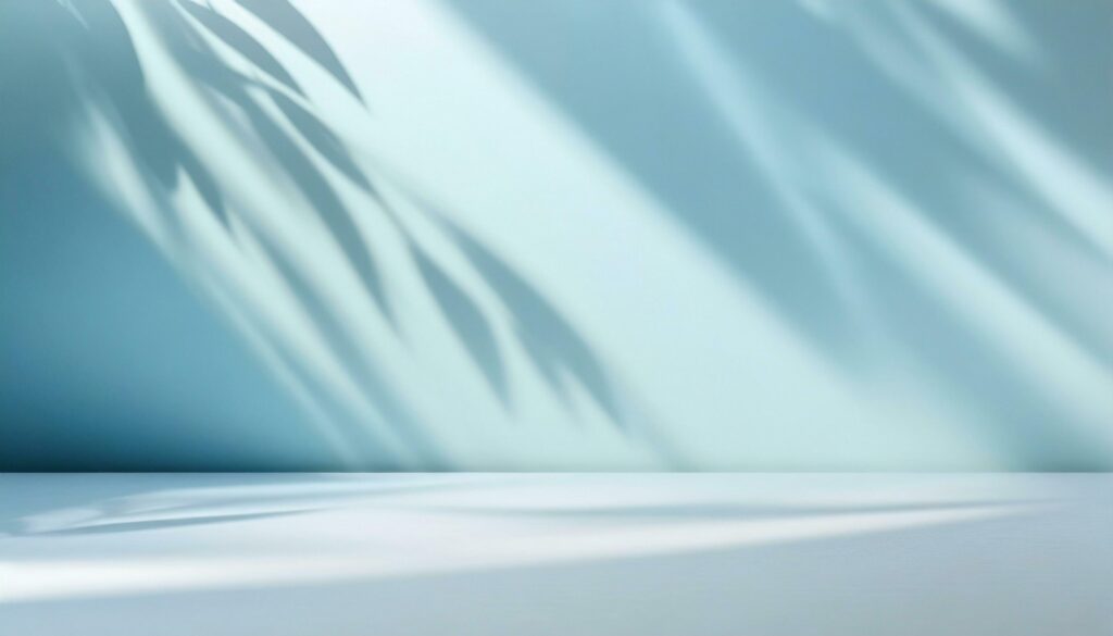 Elegant and delicate abstract light blue backdrop for product display featuring delicate and delicate shadows cast by tree limbs on the wall. Stock Free