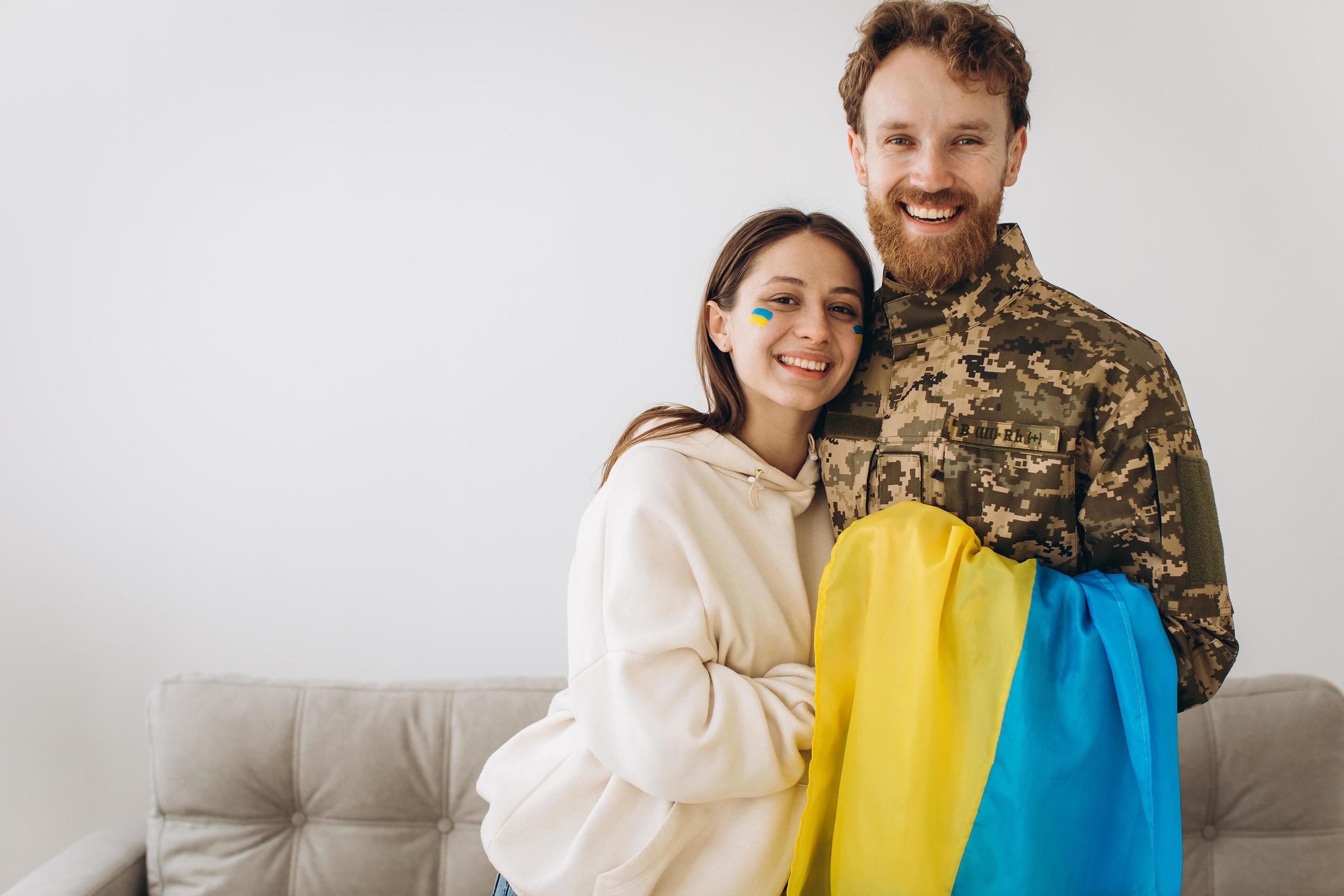 Happy Ukrainian couple who met after the war. A bearded military man in uniform hugs his happy wife at home. Stock Free