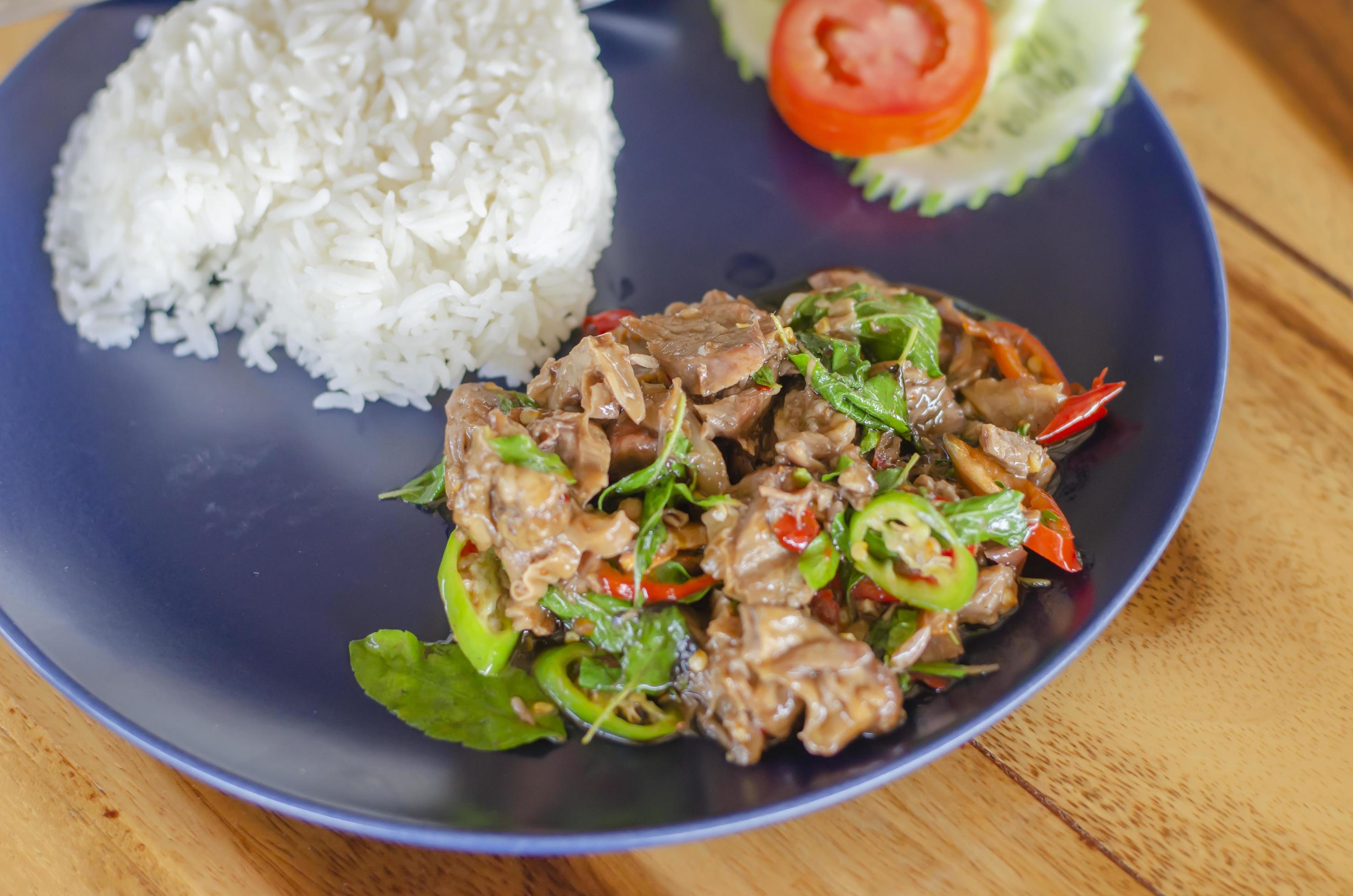 Stir Fried Basil with Stewed Pork on Rice popular thai food with wooden table background. side view Stock Free