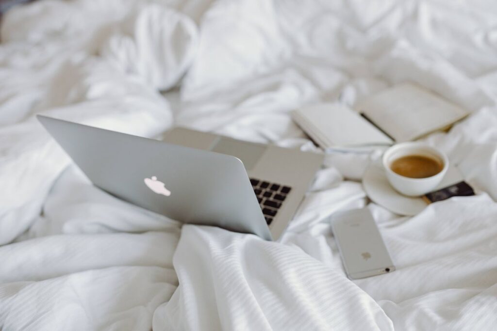 Woman working on a laptop while enjoying a breakfast coffee and chocolate in bed Stock Free