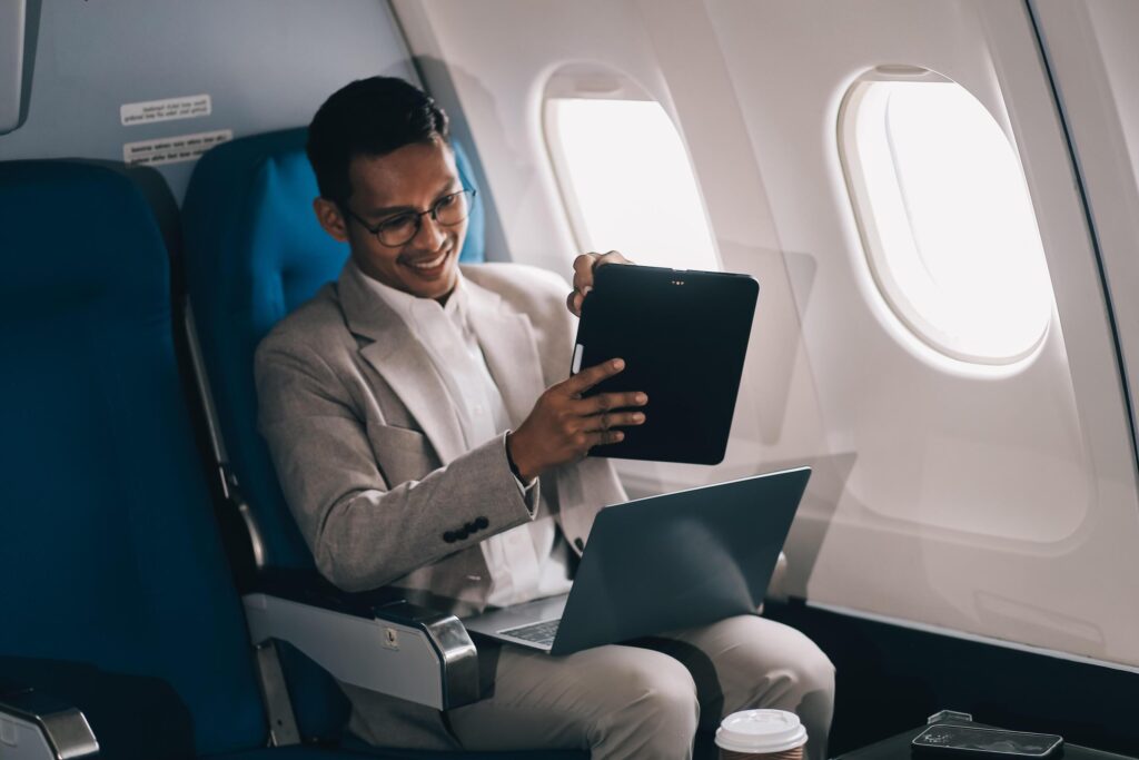 Airplane, travel and portrait of businessman working on laptop computer and smartphone while sitting in airplane. Stock Free