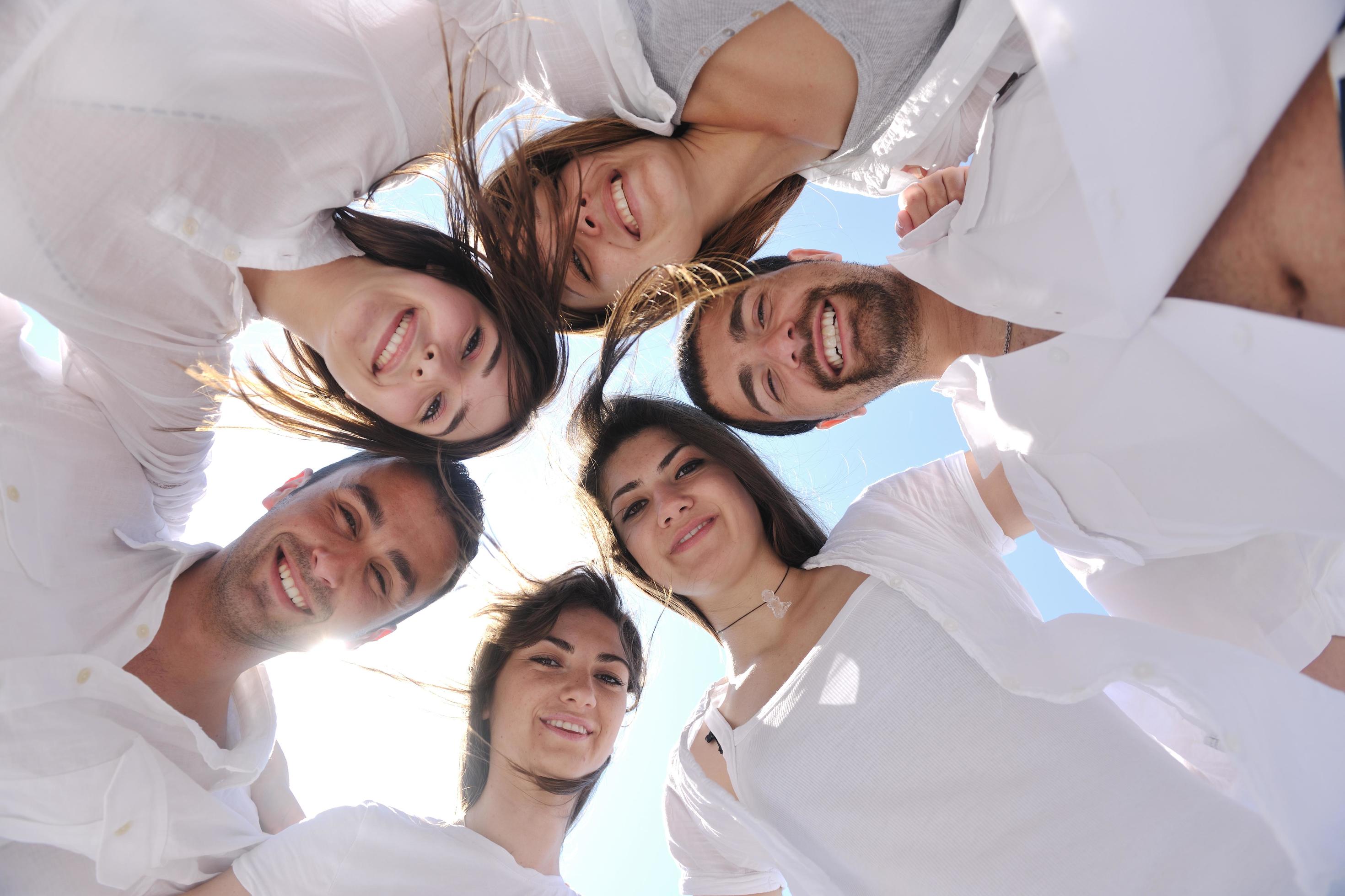 Group of happy young people in circle at beach Stock Free