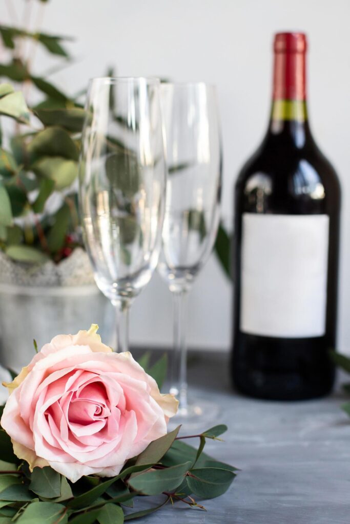 Composition with glass, flowers and bottle of vine on grey concrete background. Stock Free