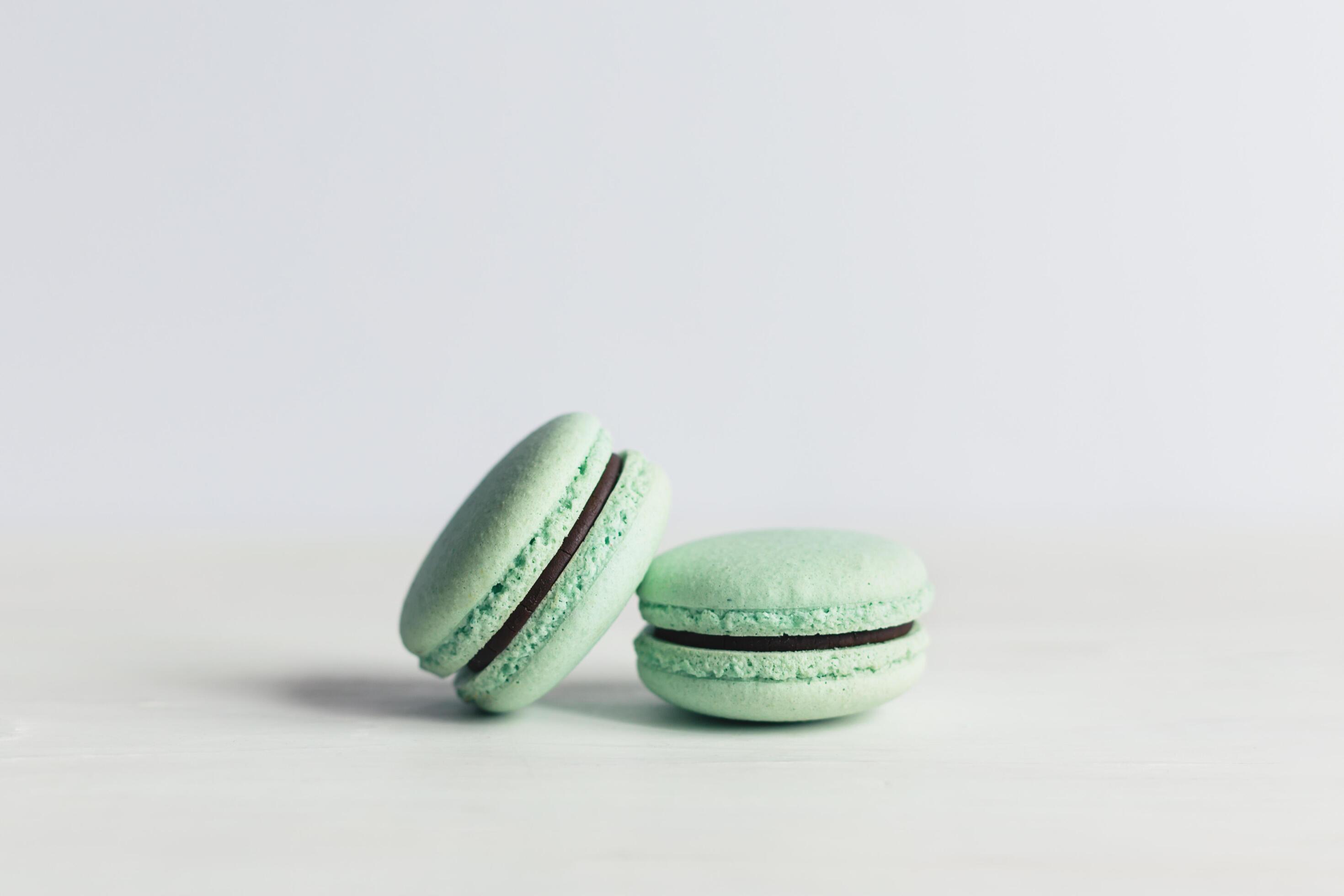 Two French macarons on a white wooden table. Mint macarons. White background. Stock Free