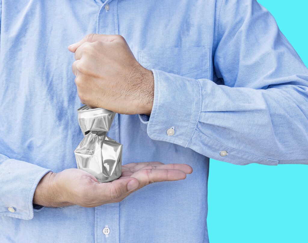 Man wear blue shirt hand hold compressed shiny aluminum can isolated on blue background. Stock Free