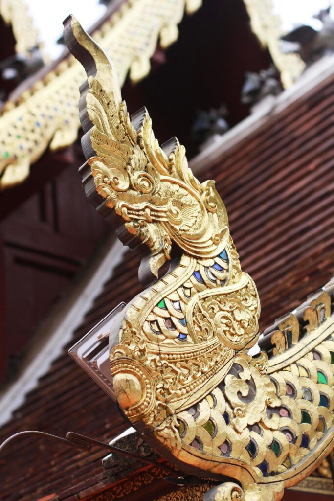 Golden naga on Art Roof of Buddhist temple with blue sky in Thailand Stock Free