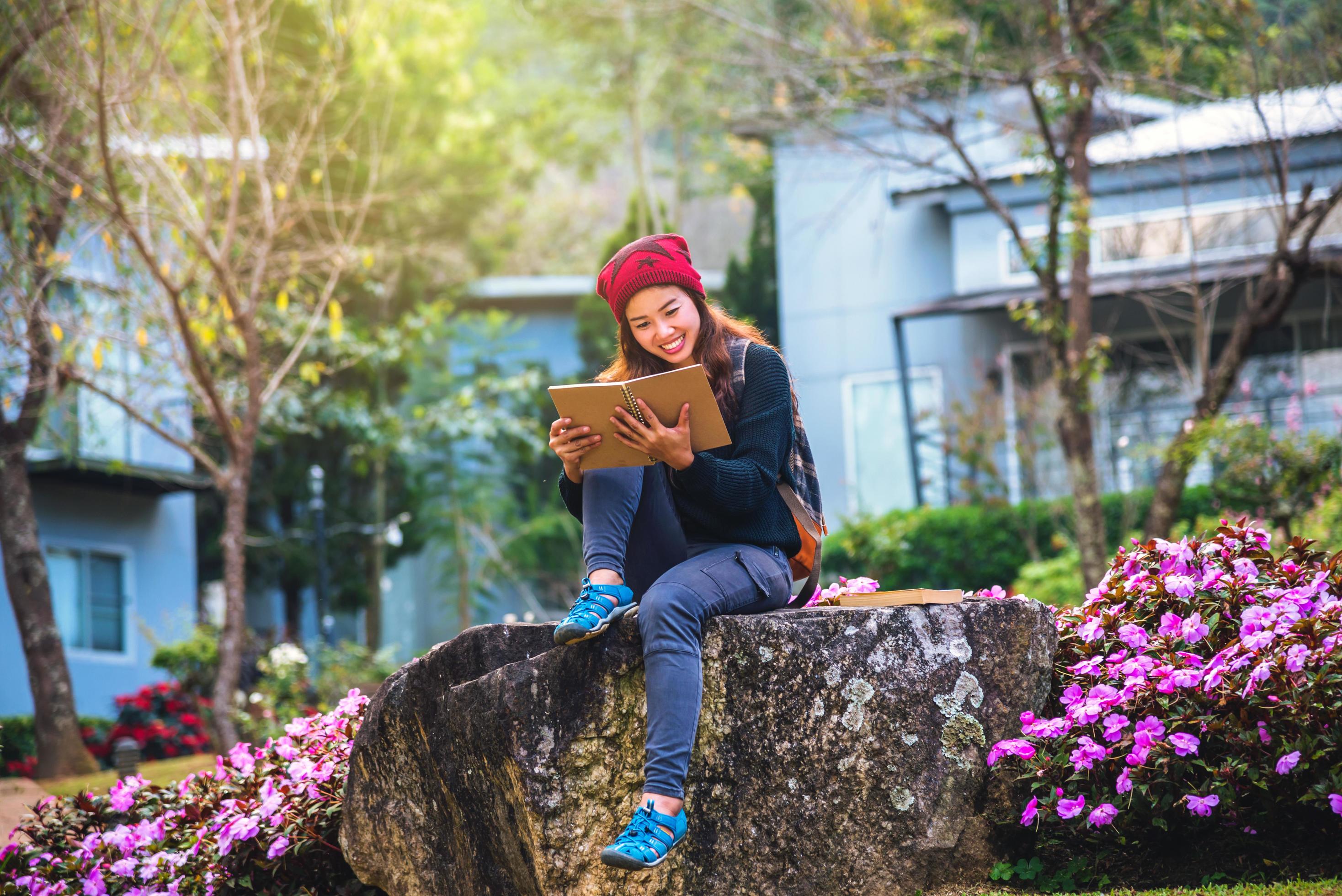 woman travel nature in the flower garden. relax sitting on rocks and reading books In the midst of nature at doi Inthanon. Stock Free