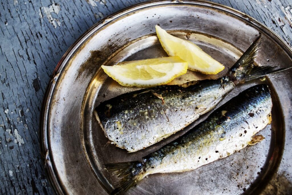 Sardines and Lemon on a Metal Plate with Broken Paint Wooden Background Stock Free